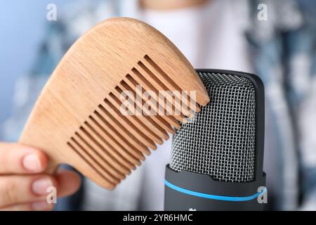 Frau, die ASMR-Geräusche mit Mikrofon und Holzkamm macht, Nahaufnahme Stockfoto