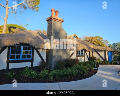 Ein charmantes Reetdachhaus mit rustikalem Holzrahmen und hellblauen Fenstern, umgeben von Grün an einem klaren sonnigen Tag. Stockfoto