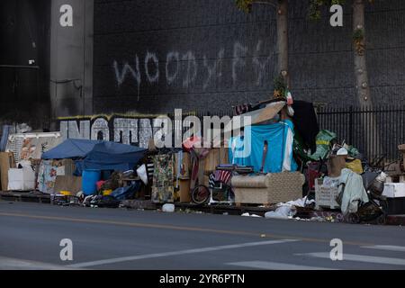 Los Angeles, Kalifornien, USA - 29. November 2024: Ein Obdachloses Lager überquert einen Bürgersteig in der Innenstadt von Los Angeles. Stockfoto