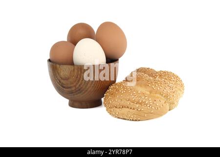 Schüssel mit Eiern in verschiedenen Farben und geflochtenem Sesambrötchen isoliert auf weißem Hintergrund Stockfoto