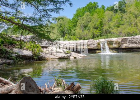 Malerischer Blick auf einen kleinen Wasserfall allein auf die Felsen, umgeben von Bäumen und Vegetation. Foto im McKinney Falls State Park in Austin Texas Stockfoto