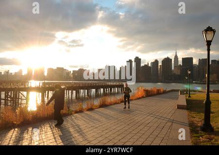 New York, Usa. Dezember 2024. Die Menschen laufen im Gantry Plaza State Park in Long Island City, Queens, New York City, während die Skyline von Manhattan im Hintergrund zu sehen ist. Quelle: SOPA Images Limited/Alamy Live News Stockfoto