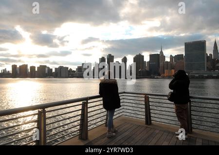 New York, Usa. Dezember 2024. Menschen stehen im Gantry Plaza State Park in Long Island City, Queens, New York City, während die Skyline von Manhattan im Hintergrund zu sehen ist. Quelle: SOPA Images Limited/Alamy Live News Stockfoto