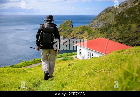 Man wandert auf dem Cape Brett Track. Cape Brett Hut in der Ferne. Bay of Islands. Neuseeland. Stockfoto