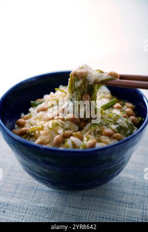 Reis mit Natto und Mekabu, mit Essstäbchen hochgehoben Stockfoto