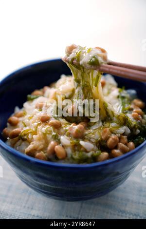 Reis mit Natto und Mekabu, mit Essstäbchen hochgehoben Stockfoto