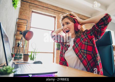 Gestresste junge Frau, die auf laute Musik in Kopfhörern reagiert Stockfoto