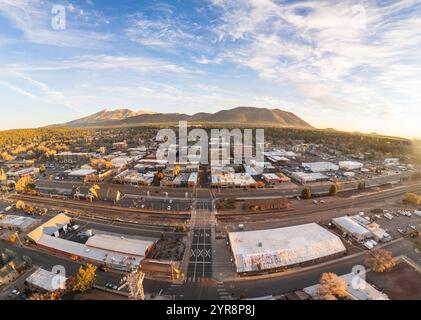Luftpanoramablick auf die Innenstadt von Flagstaff, Arizona, bei Sonnenaufgang im Herbst, mit dem Stadtzentrum, dem Bahnhof und den San Francisco Peaks Stockfoto