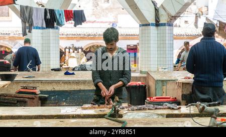 Essaouira, Marokko - 17. September 2022: Marokkanische Fischer reinigen und bereiten einen Tintenfisch zum Verkauf auf dem Essaouira-Fischmarkt vor Stockfoto