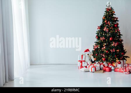 Weihnachtsbaum mit Geschenken, dekoriert mit roten Spielzeuggirlanden im Inneren für das neue Jahr Stockfoto