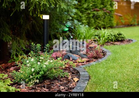 Atemberaubend schönes Gartenbett mit Felsen und lebendigen Pflanzen mit Pflege Stockfoto