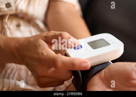 Erfassen eines detaillierten Bildes der Hände einer Frau mit einem tragbaren Blutdruckmessgerät zur Überwachung der kardiovaskulären Gesundheit und Beurteilung des Wohlbefindens Stockfoto
