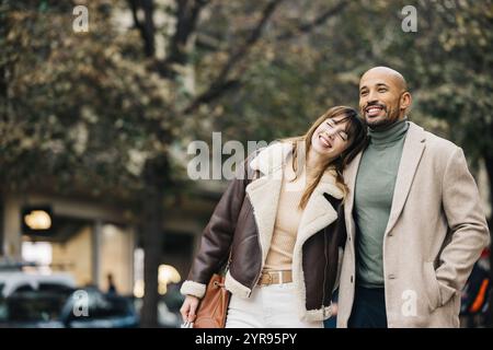 Ein liebevolles Paar genießt einen sonnigen Einkaufsbummel in der Stadt und teilt Lachen und Wärme. Stockfoto