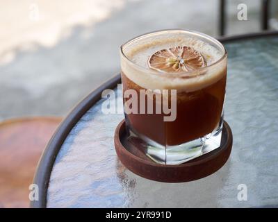Frischer Orangeneiskaffee serviert mit getrockneten Orangenscheiben garniert auf dem Tisch im Freien Stockfoto