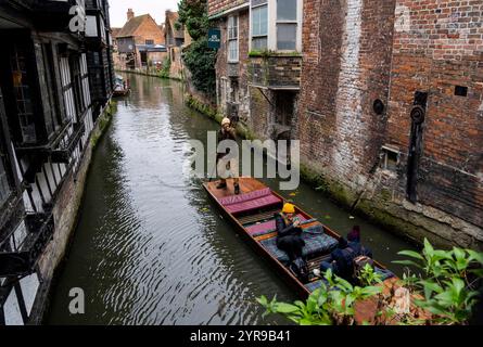 Touristen machen eine historische Bootstour auf dem Fluss Stour durch Canterbury. Der Great Stour könnte behaupten, Englands historischster Fluss zu sein. In römischer und mittelalterlicher Zeit war der Fluss eine wichtige Verkehrsroute, die Canterbury mit dem europäischen Festland verband. Die Stadt gehört zum UNESCO-Weltkulturerbe in der Grafschaft Kent, England, war bis 1974 County Borough und liegt am Fluss Stour. Canterbury ist eine Stadt und UNESCO-Weltkulturerbe in der Grafschaft Kent, England; es war bis 1974 County Borough. Er liegt am Fluss Stour. Stockfoto