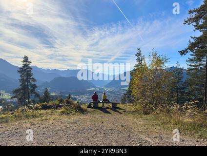 Wanderer, Touristen und Wanderer mit Hunden auf der Dürrenberg Alm mit Blick auf das Lechtal mit dem Lech und dem Hahnenkamm in Reutte, Österreich am 1. November 2024 Stockfoto