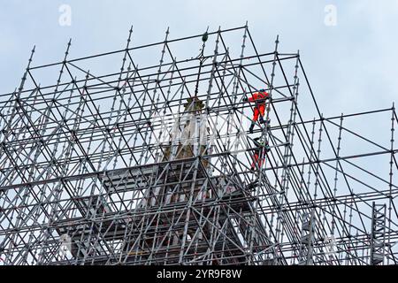 Zwei Fachkräfte mit Sicherheitsausrüstung, die Gerüste an der Spitze der Kirche St. Thomas von Canterbury installieren, um den beschädigten Turm zu restaurieren. Stockfoto