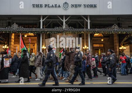 Ein Mann hält vor dem Plaza Hotel ein Schild mit der Aufschrift "Tax Payer Against Arms". Hunderte pro-palästinensischer Demonstranten versammeln sich am Columbus Circle zum "Internationalen Tag der Solidarität für das palästinensische Volk" in New York City. Stockfoto