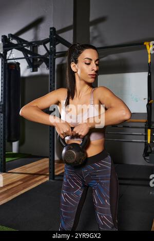 Eine engagierte Frau trainiert mit einer Kettlebell und zeigt Kraft und Entschlossenheit im Fitnessstudio. Stockfoto