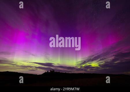 Silhouette von Dunstanburgh Castle mit einer spektakulären Aurora darüber. Northumberland, England, Großbritannien. Stockfoto