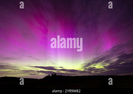 Silhouette von Dunstanburgh Castle mit einer spektakulären Aurora darüber. Northumberland, England, Großbritannien. Stockfoto