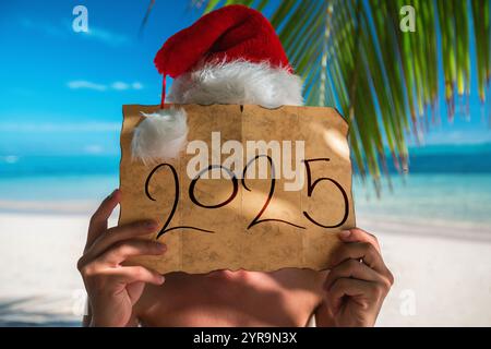 Neujahrsurlaub 2025 auf einer tropischen Insel. Touristenmann mit Santa Claus Hut und alter Schatzkarte. Punta Cana Beach, Dominikanische Republik. Stockfoto