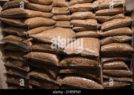 Holzpellets, verpackt in 15-kg-Beuteln. Holzpellets in Plastiktüten gestapelt. Heizöl wird dem Haushalt zur Heizung des Innenraums im Winter zugeführt. Stockfoto