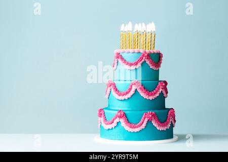 Gestufte Geburtstagskuche mit rosa verzierten Buttercremeschnörkeln und goldenen Geburtstagskerzen Stockfoto