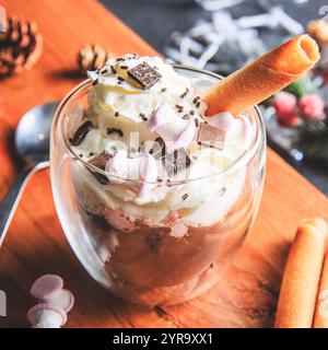 Traditionelle heiße Schokolade mit Schlagsahne, Marshmallows und Schokoladenspänen in einer Weihnachtsdekoration im Studio Stockfoto