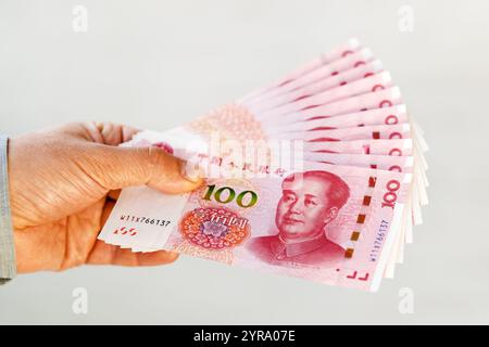 Handauflage mit 100 Yuan-Noten. Übersetze das Alphabet Yibai Yuan, was hundert Yuan bedeutet. Stockfoto