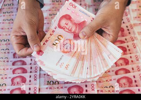 Handstapel mit 100 Yuan-Noten auf dem Tisch. Übersetze das Alphabet Yibai Yuan, was hundert Yuan bedeutet. Stockfoto