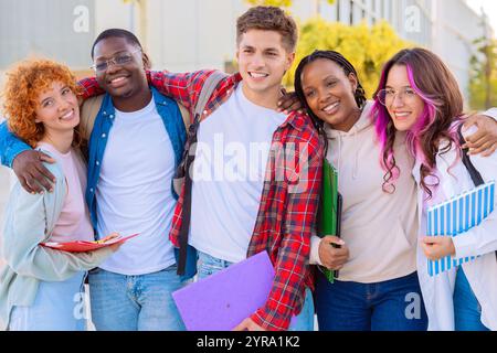 Verschiedene Schülergruppen lächeln und posieren gemeinsam mit Notizbüchern im Freien Stockfoto