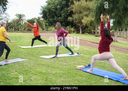 Multirassische Seniorinnen machen Yoga-Übungen im Freien mit Stadtpark im Hintergrund - gesunder Lebensstil und fröhliches älteres Lebensstil Konzept - Fokus auf Stockfoto
