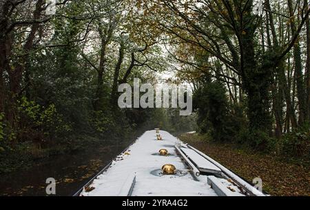 Blick aus dem Schmalboot, das im Winter durch die englische ländliche Landschaft auf dem britischen Kanal fährt, während es schneit Stockfoto