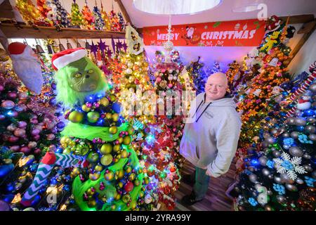 Rinteln, Deutschland. Dezember 2024. Thomas Jeromin steht inmitten von Weihnachtsbäumen in seinem Haus im Stadtteil Schaumburg. 600 Weihnachtsbäume und weit über 108.000 Weihnachtskugeln: In der Adventszeit erstrahlt das Haus der Familie Jeromin als farbenfrohe Weihnachtswelt. Das Rekordinstitut für Deutschland hat die Familie „für die am meisten dekorierten Weihnachtsbäume an einem Ort“ ausgezeichnet. Quelle: Julian Stratenschulte/dpa/Alamy Live News Stockfoto