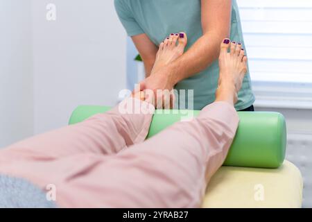 Frau mit Knöchelschmerzen in der Physiotherapie. Chiropraktiker-Untersuchung bei verletzten Sprunggelenken. Stockfoto