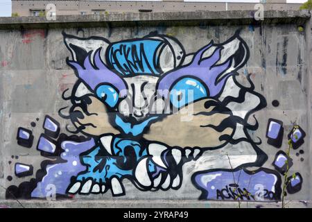 Graffiti, Inschrift, Zeichnung des Kopfes einer bösen Katze, eines Tigers von blau, lila, weiß, pfirsichfarben mit großen weißen Zähnen, schwarzen Barthaaren. Stockfoto