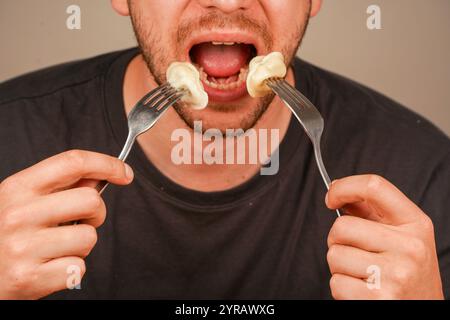 Ein fokussiertes Bild von Knödeln auf einer Gabel, die von einer Person genossen werden, symbolisiert das Vergnügen, frisch zubereitete Komfortgerichte zu essen. Ein Mann isst Stockfoto