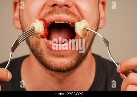 Ein fokussiertes Bild von Knödeln auf einer Gabel, die von einer Person genossen werden, symbolisiert das Vergnügen, frisch zubereitete Komfortgerichte zu essen. Ein Mann isst Stockfoto