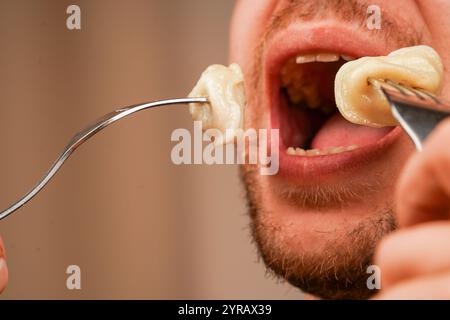 Ein fokussiertes Bild von Knödeln auf einer Gabel, die von einer Person genossen werden, symbolisiert das Vergnügen, frisch zubereitete Komfortgerichte zu essen. Ein Mann isst Stockfoto