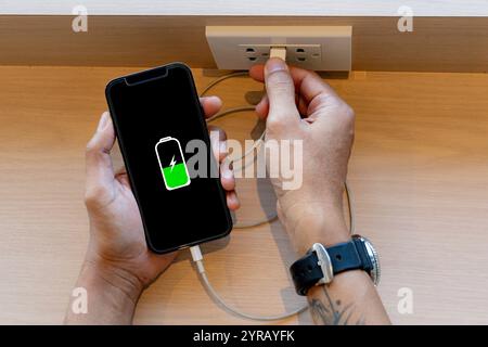 Handheld-Smartphone, das zum Aufladen mit Strom verbunden wird Stockfoto