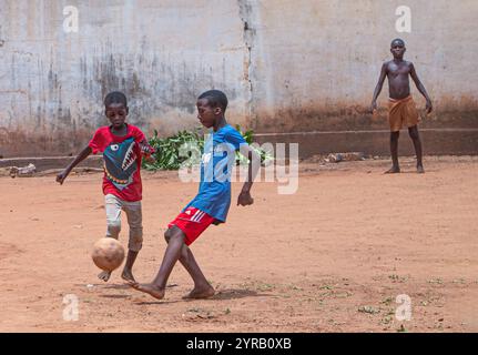 Kinder spielen Fußball auf einem staubigen Feld in einem ländlichen Dorf in Togo Stockfoto