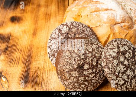 Rundes Weizenbrot und kleine Roggenbrötchen auf hölzernem Hintergrund. Leerzeichen für Text. Hochwertige Fotos Stockfoto