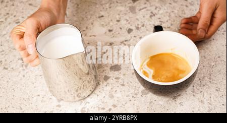 Eine Frau hält einen Metallkrug für Milch in den Händen. Nahaufnahme des Barista Milchkännchens. Getränke im Café. Ein heißes Getränk. Ausrüstung für die Zubereitung von Kaffee. Cafe Stockfoto