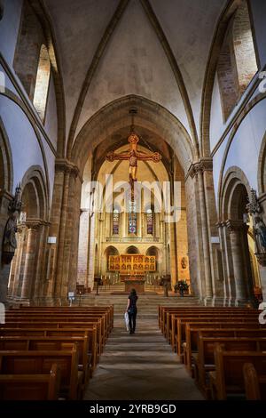 Eine Frau geht zum Altar in einer wunderschönen Kirche in Osnabrück, Deutschland, mit atemberaubenden Buntglasfenstern und Holzbänken. Stockfoto