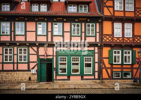 Ein charmantes historisches Gebäude in Quedlinburg, Deutschland, mit einer Mischung aus rosa und orangen Fachwerkarchitektur mit dekorativen Elementen und einem W Stockfoto