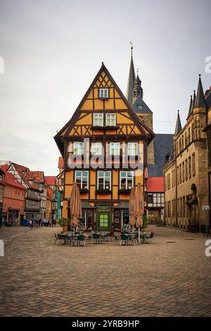 Ein bezauberndes historisches Gebäude in Quedlinburg, Deutschland, mit einem unverwechselbaren Fachwerkdesign, steht auf einem Kopfsteinpflasterplatz, umgeben von anderen gebäuden Stockfoto