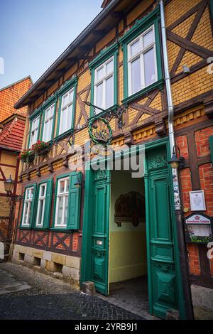 Ein charmantes historisches Gebäude in Quedlinburg, Deutschland, mit einer Mischung aus Holzrahmen und bunten Ziegelsteinen, grünen Fensterläden und einem Profi Stockfoto