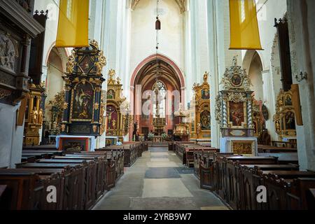Das Innere einer historischen Kirche in Torun mit verzierten Altären und Holzbänken. Stockfoto