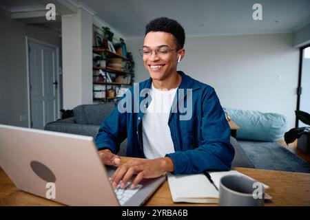 Afroamerikanischer Schüler, der Musik hört, während er seine Schularbeit verrichtet Stockfoto